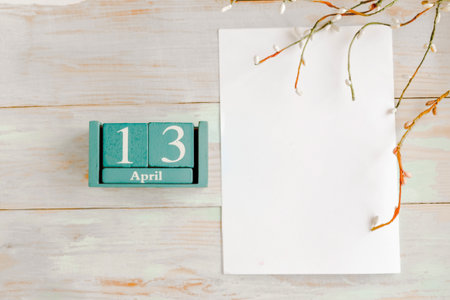 April 13. Blue cube calendar with month and date and white mockup blank on wooden backgroundの写真素材