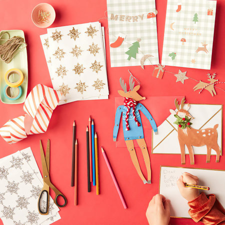 Flat lay of woman making christmas decorations on red background.の写真素材