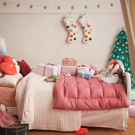 Beautiful young woman lying on the bed with Christmas gifts in her bedroomの写真素材