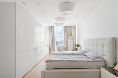 Interior of a modern bedroom with white walls, wooden floor and big bedの写真素材