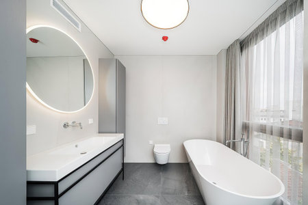 Interior of a modern bathroom with white walls, concrete floor and white bathtubの写真素材