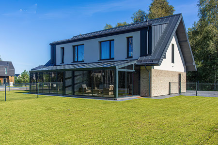 Modern house with solar panels installed on the roof and green grass.の写真素材