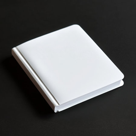 A simple white notebook, album or diary isolated on a black background. Blank album with white spiral stitched coverの素材