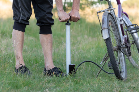 A cyclist pumps air into the wheel using a manual autonomous pump.Inflating the bicycle tire.The...