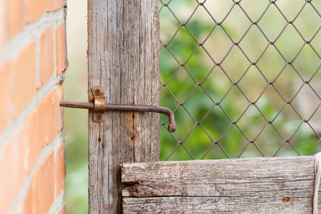 Old metal homemade gate valve on a mesh door in a village yard.The concept of village life.の写真素材
