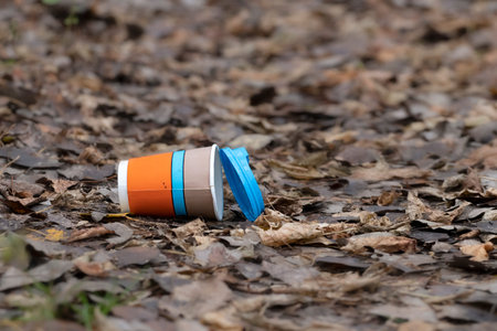 Trash in the forest.Used disposable paper coffee cup in the forest. Take away food industries impact...