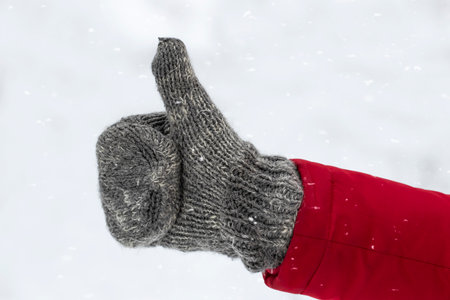 Male hand in knitted mittens.Man showing thumbs up.Winter love concept.の写真素材