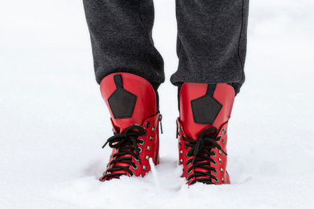 Female feet in red shoes in deep snow.Winter walking in snow.の写真素材