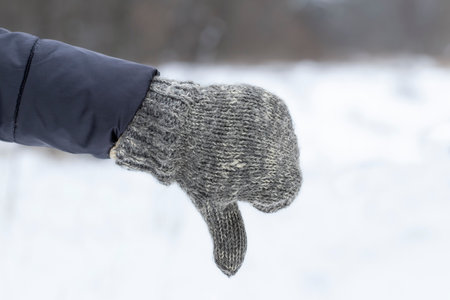 Female hand in knitted mitten.Girl in mitten shows thumbs down.Concept of dislike for winter.の写真素材