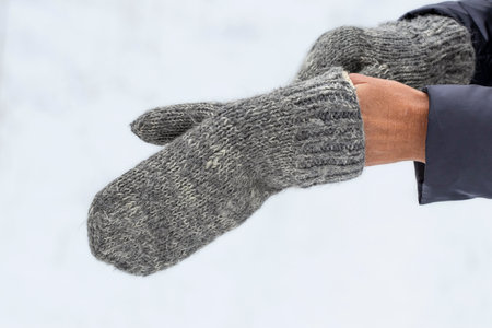A girl puts on knitted mittens on the street in winter.Warm clothes for winter walks.の写真素材