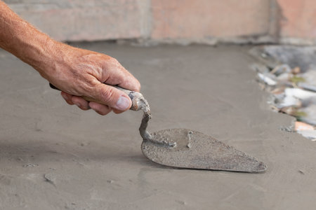 Cementation of a garden path.A man manually spreads the cement mixture with a trowel.Spring work in the garden.の写真素材