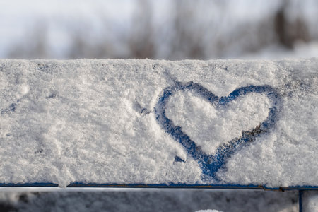 A big heart painted on fluffy snow on a bench. The concept of love.の写真素材