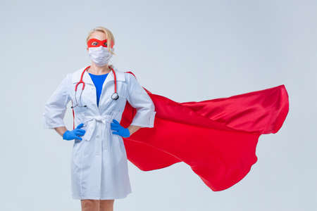 Young beautiful woman hospital doctor wearing red superhero clothing isolated on light backgroundの写真素材