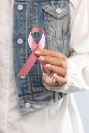 Healthcare and medicine concept - closeup woman hands holding pink breast cancer awareness ribbon.
