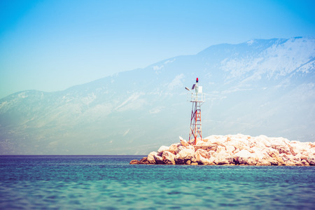 Sea beacon on rocky shore on sunriseの写真素材