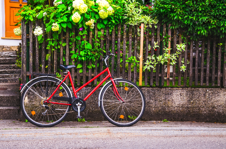 Red bike parked near old wooden fence.の写真素材