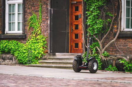 Electric personal transport standing near beautiful green building on the city streetの写真素材
