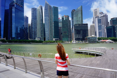 Singapore, Singapore - February 10, 2017: People walk and relax alongside the Singapore river near skyscrapers on sunny day in Singapore.のeditorial素材