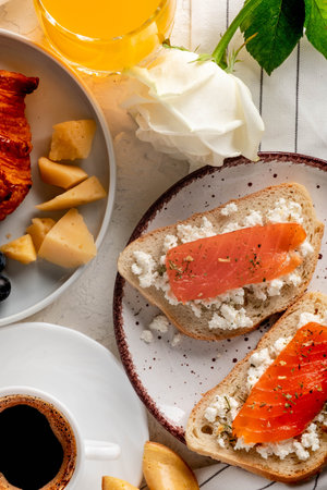Continental breakfast captured from above (top view, flat lay). Coffee, orange juice, croissant, sandwich and flowers. Close-up.の写真素材