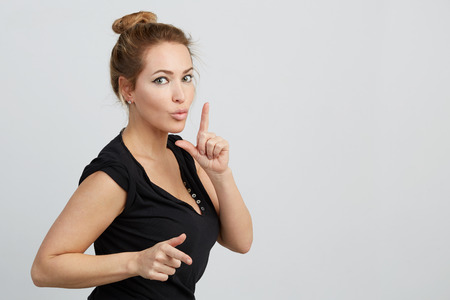 Emotional beautiful young adult woman portrait. Looking at Camera. Studio shoot. Isolated on White Background. A woman dances lifting her hands and cutting the air with her fingers.の写真素材