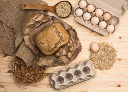 Products for a healthy diet (rye bread, cereals, eggs, walnuts, pumpkin seeds) laid out on a light wooden table against the background of burlap and rough paper, horizontal,  top view, flat layの写真素材