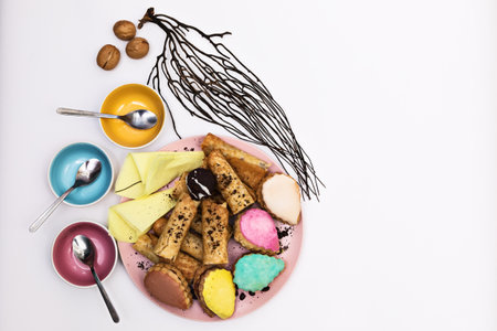 Multi-colored cakes served on a pink plate with coffee chips surrounded by colored utensils on a white background, top view, flat lay, copyspace on the right, horizontalの写真素材