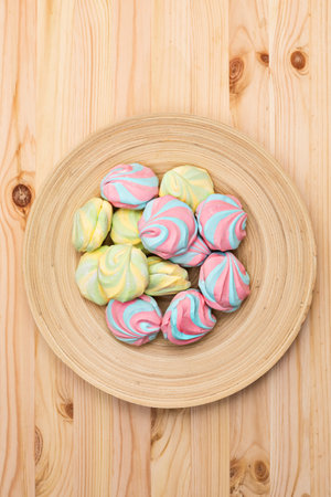 Colorful fluffy marshmallows on a platter on a wooden background, close-up, flat lay, top view, vertical, copyspaceの写真素材
