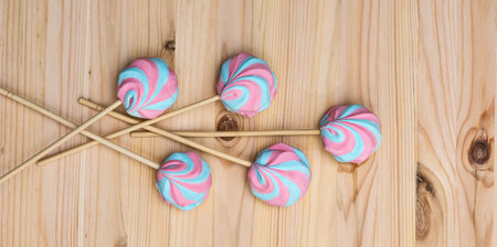 Colorful fluffy marshmallows on sticks on a background of a light wooden surface, close-up, flat lay, top view, horizontalの写真素材