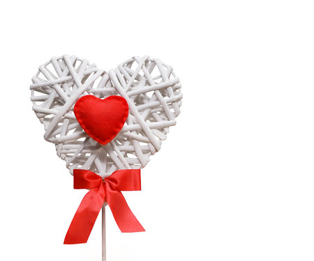 Decorative braided white heart with red shiny bow, isolate on a white background, close-up, top viewの写真素材