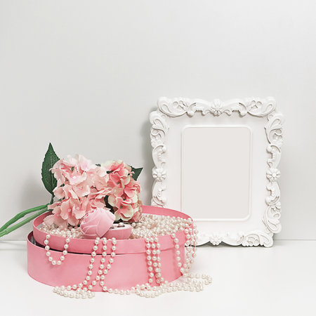 Composition of a box with pearl beads, a bouquet of flowers and a box with female jewelry and an elegant white frame with empty space, mockup in pale pink tones copy spaceの写真素材