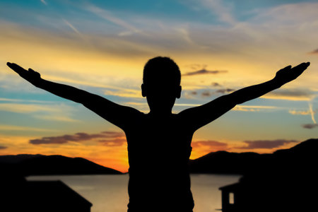 Natural silhouette of a person with open raised arms at sea sunset in summertimeの写真素材