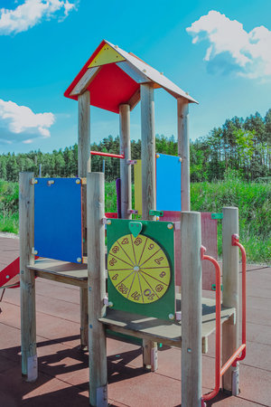 Brightly colored wooden and plastic playground equipment with a ladder, slide, and other features...