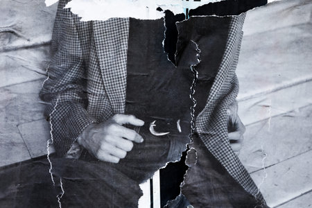 A stylish man in a classic suit and jeans confidently poses against a rustic wooden fence backdrop, exuding charm and confidence in a fashionable setting.の写真素材