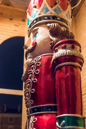 A beautifully crafted toy nutcracker figurine in red and green attire with a golden crown, standing...