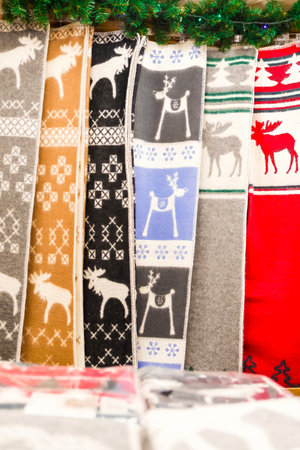Colorful Scandinavian blankets featuring elaborate patterns and playful reindeer motifs are on display at a lively market stall, creating a vibrant and festive atmosphere.の写真素材