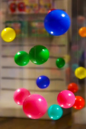 An arrangement of various colored balls hanging by strings against a blurred background. The balls are in an array of colors, including blue, green, yellow, pink, and red.の写真素材