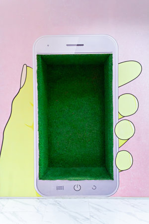 A phone-shaped box with a bright green interior sits on a colorful background, displaying playful artistry. Ideal for organizing small items, it adds a fun touch to any space.の写真素材