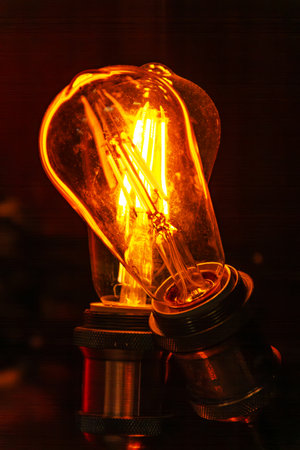 A vintage light bulb radiates a warm amber glow, enhancing the ambiance of a snug corner. Its intricate design adds charm, casting soft shadows that invite relaxation and contemplation.の写真素材