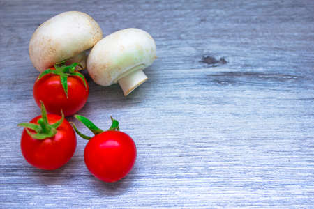 Mushrooms and tomatoes lie on a gray background.の写真素材
