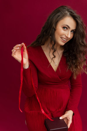 Curly woman in red dress opened box with stripe.