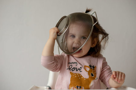 Baby girl play with colander and have fun.
