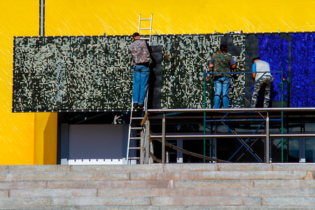Three workers install an advertising billboardの写真素材