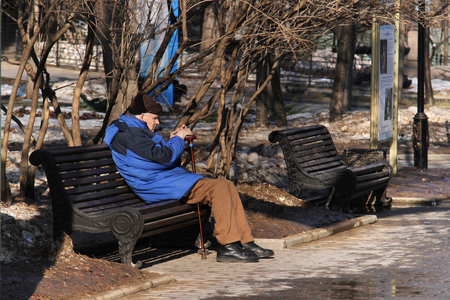 MOSCOW, RUSSIA - MARCH 11, 2015: Elderly man sitting on wooden bench in Catherine Park on a sunny dayのeditorial素材
