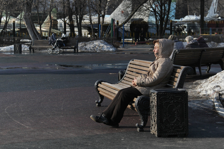 MOSCOW, RUSSIA - MARCH 11, 2015: Older woman sitting on wooden bench in Catherine Park on a sunny dayのeditorial素材