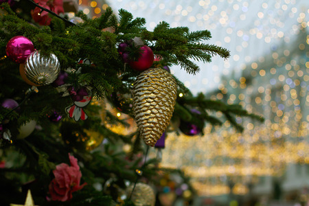 Christmas toy bump and balls hanging on tree branch on the background of golden lightsの写真素材