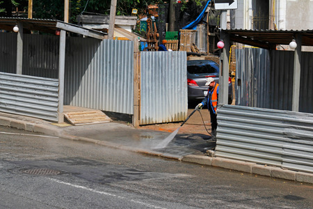 Moscow, Russia - July 07, 2015: Worker cleaning driveway with high pressure washer in Moscowのeditorial素材