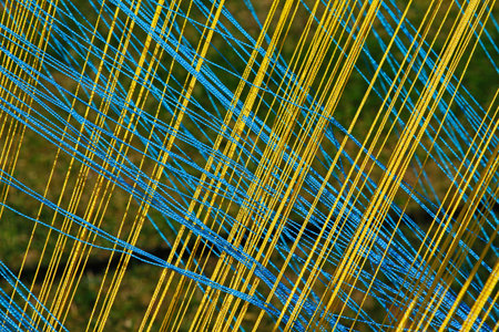 Abstract background of yellow and blue thread intersecting diagonally