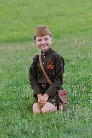 Volgograd, Russia - May 9, 2012: A little girl in a military uniform sitting on the grass on Victory Day celebration in Volgogradのeditorial素材