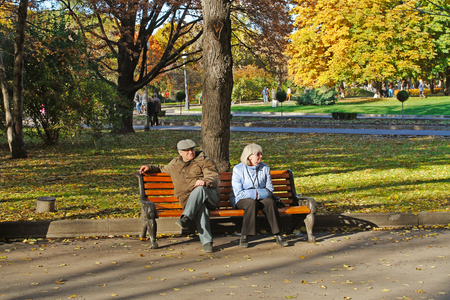 Moscow, Russia - October 12, 2013: Elderly couple sitting on bench in autumn park Gorkogo in Moscowのeditorial素材