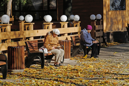 Moscow, Russia - October 21, 2015: Senior women sitting on wooden bench and reading a book in Fili park in Moscowのeditorial素材